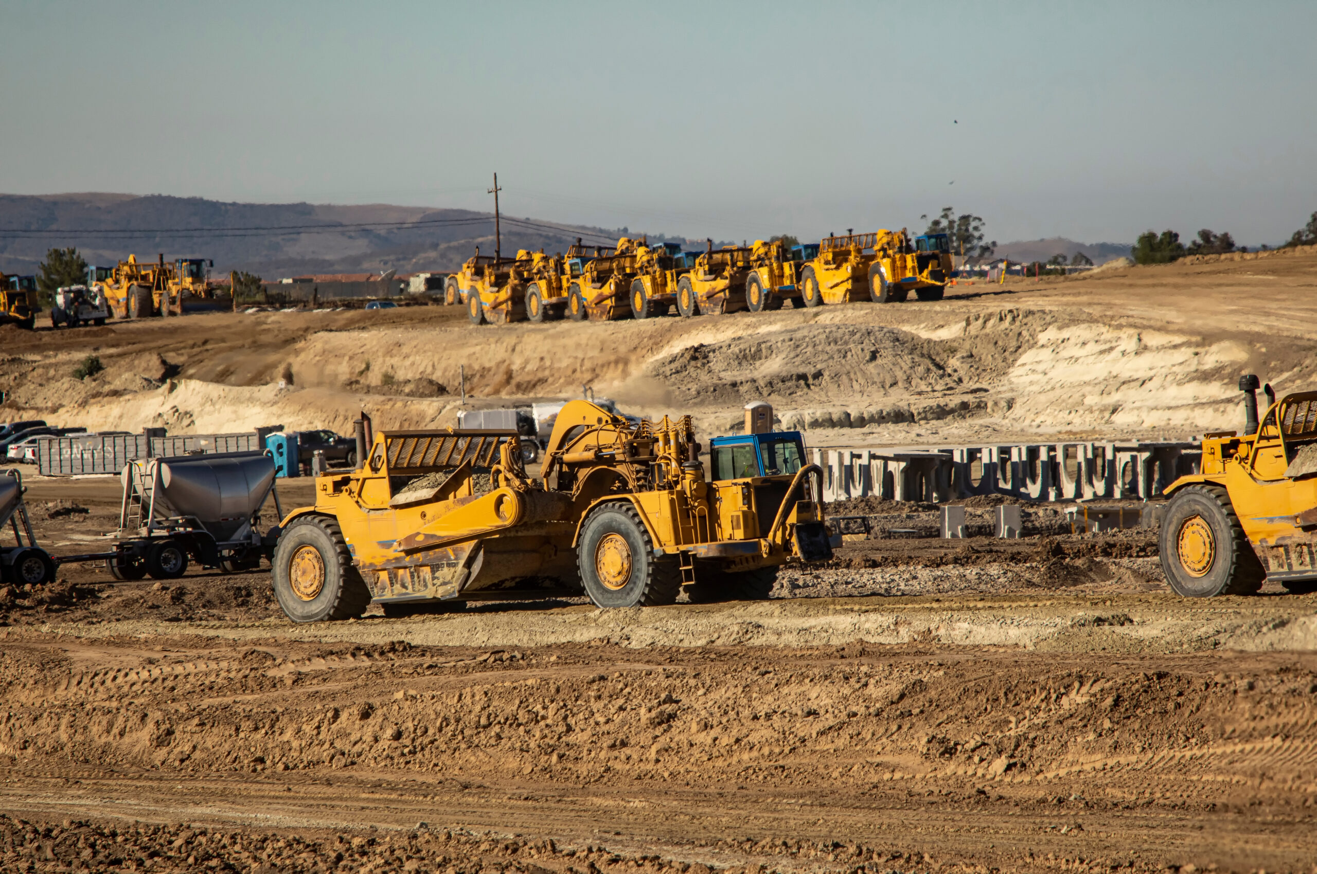 Earth moving equipment at a construction grading site with other tractors lined up in the background